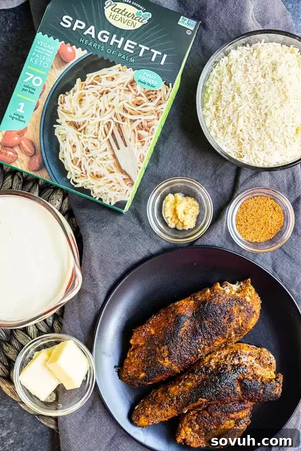 All the fresh ingredients laid out for making Keto Cajun Chicken Alfredo Pasta, including chicken, heavy cream, parmesan, and heart of palm noodles.