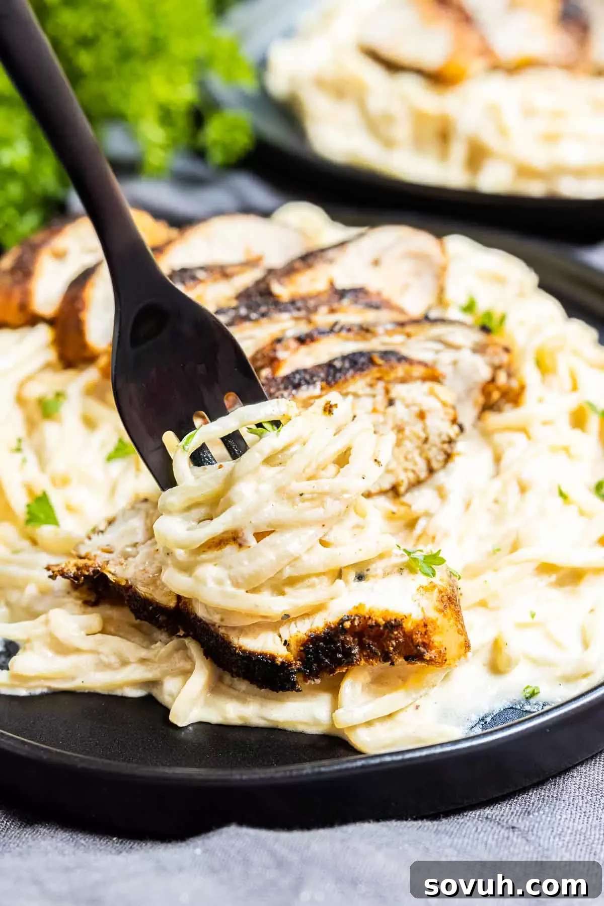 A close-up of a fork holding a bite of Keto Cajun Chicken Alfredo Pasta, highlighting the texture and richness.
