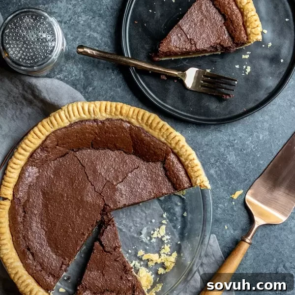 A decadent whole Chocolate Chess Pie and a slice on a plate, showcasing its rich, glossy filling.