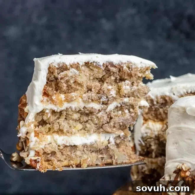 A generous slice of Hummingbird Cake being carefully removed from a full, beautifully frosted cake.