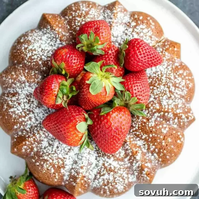 Moist Sour Cream Pound Cake with a generous center of fresh strawberries, ideal as a simple summer dessert.