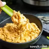 dipping celery into Instant Pot Buffalo Chicken Dip