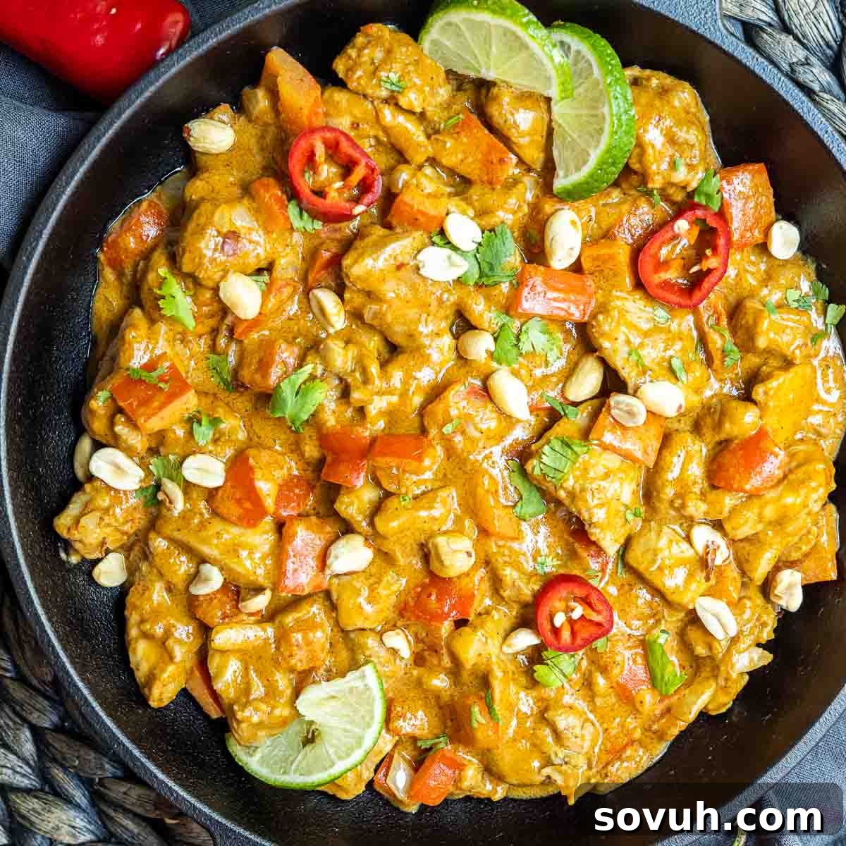Keto Peanut Butter Chicken in a cast iron skillet, garnished with fresh cilantro and crushed peanuts.
