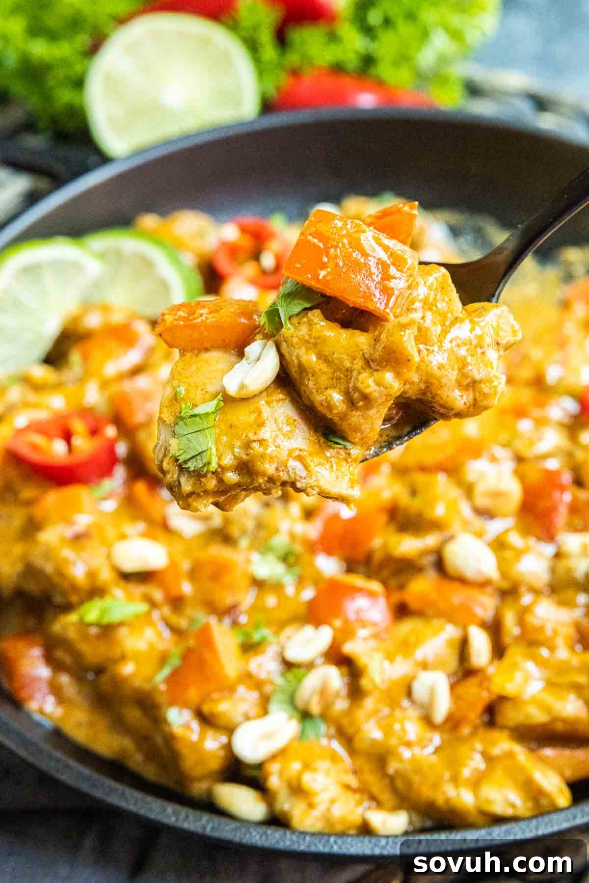 Close-up of Keto Peanut Butter Chicken garnished with chopped peanuts and fresh cilantro in a cast iron skillet.
