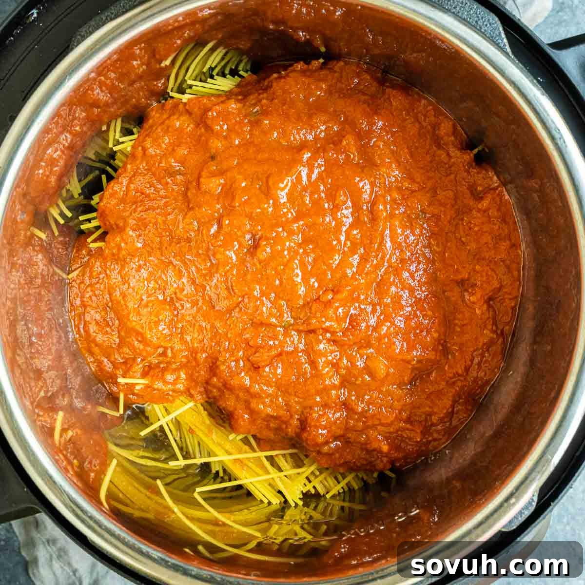 Effortless Instant Pot Spaghetti 6 Pouring marinara sauce over spaghetti and meat in an Instant Pot