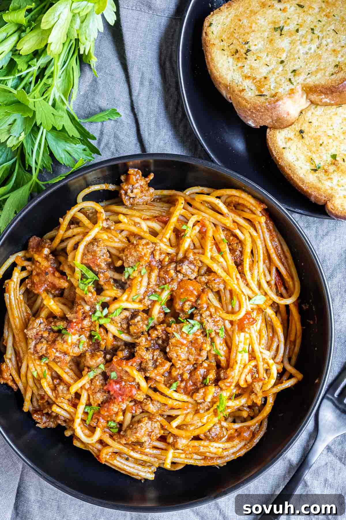 Effortless Instant Pot Spaghetti 7 Instant Pot Spaghetti served in a black bowl with garlic bread on the side