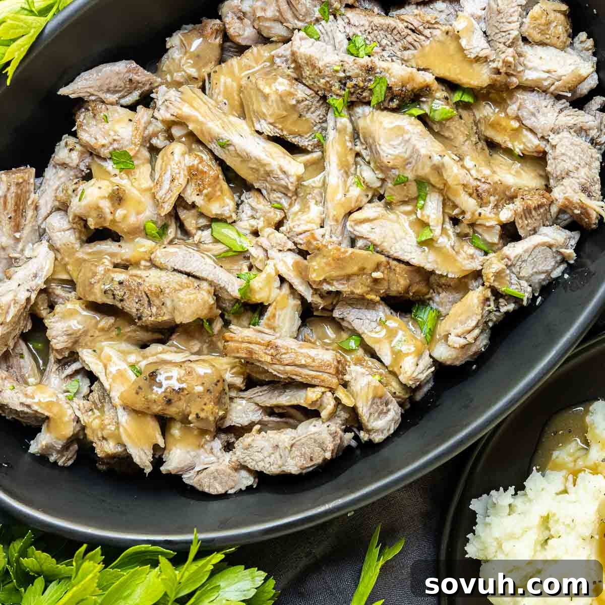 Instant Pot Pork Roast shredded in platter, served with smooth, flavorful gravy