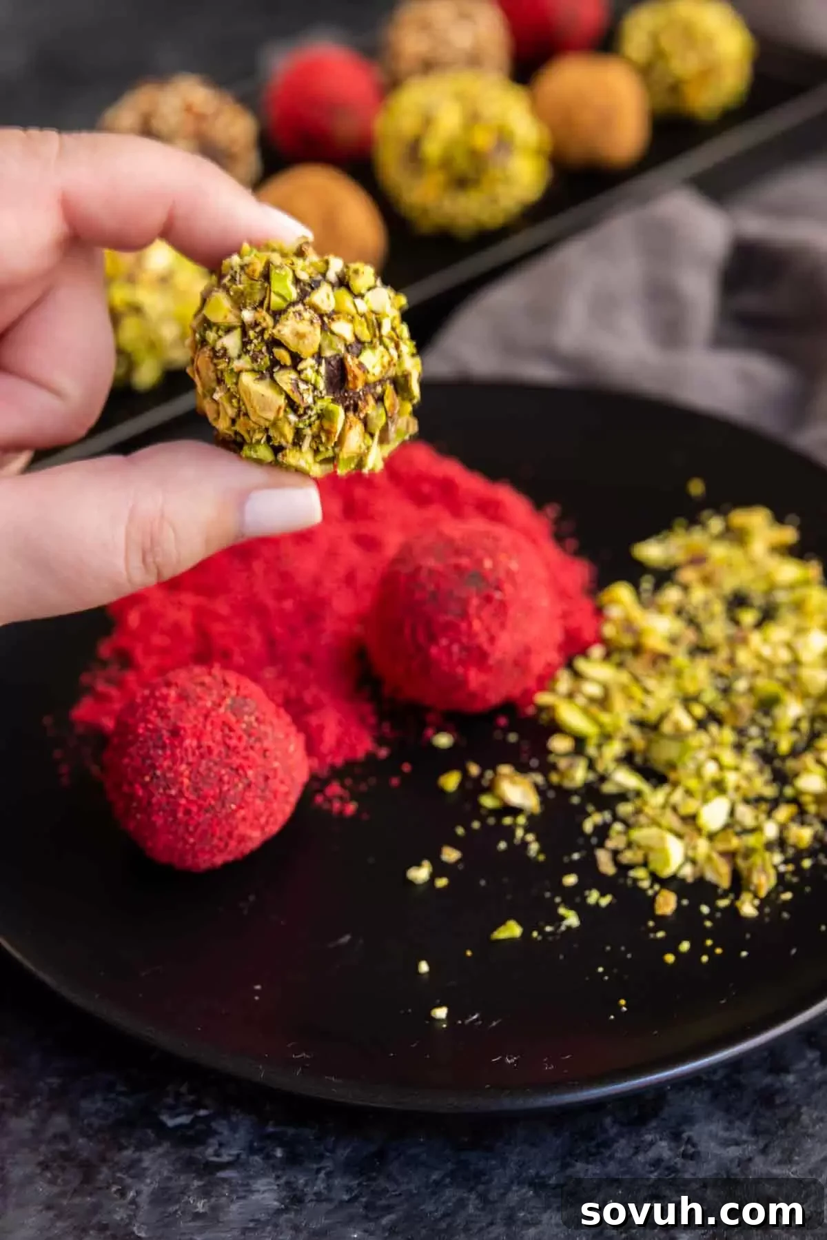 A hand holding a perfectly round homemade chocolate truffle, showcasing its smooth texture.