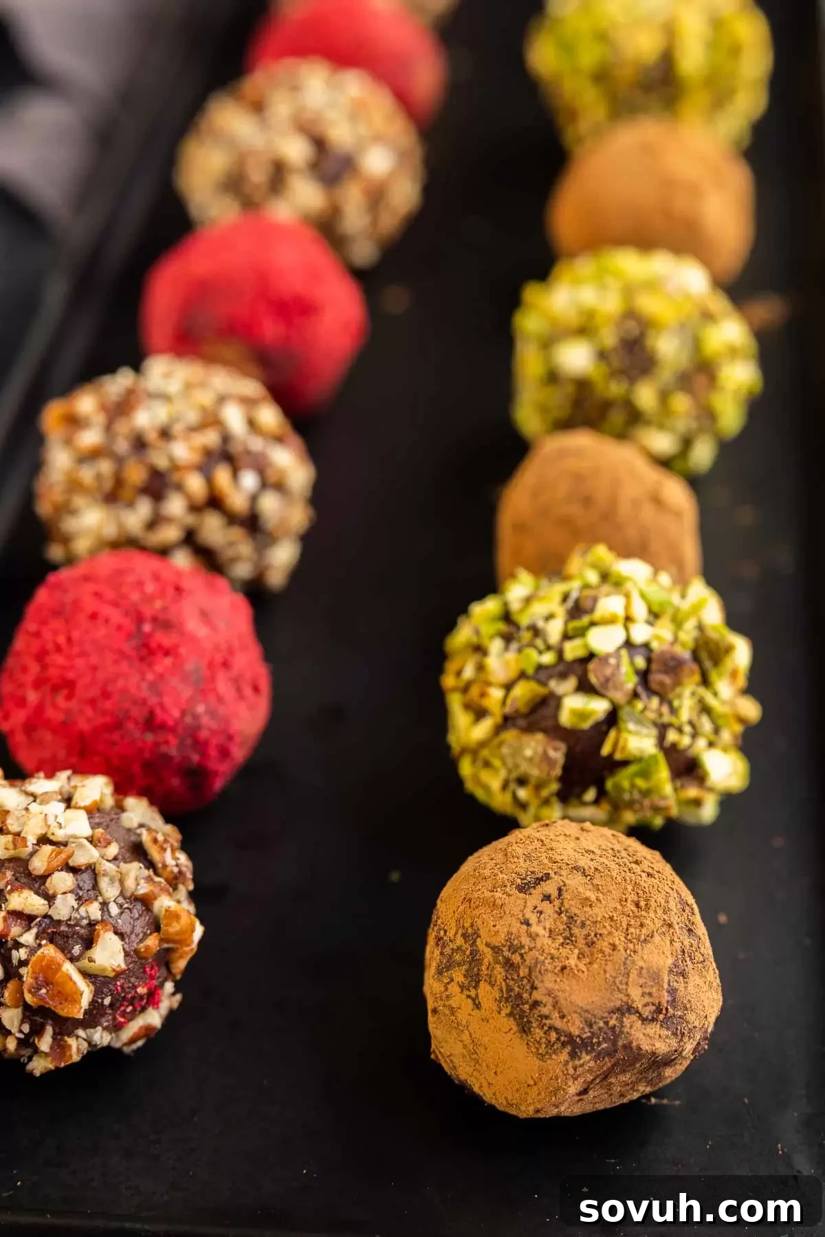 Delicious chocolate truffles coated in cocoa powder, arranged elegantly on a black platter.