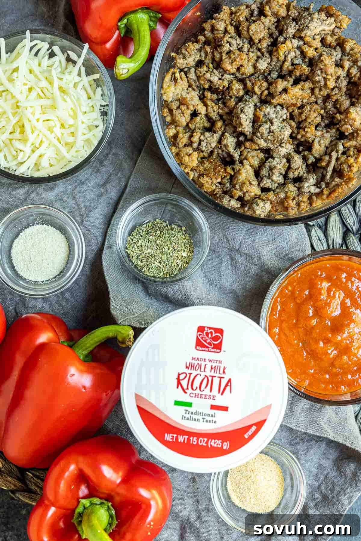 A vibrant display of ingredients laid out to make Lasagna Stuffed Peppers, including bell peppers, meats, cheeses, and spices.