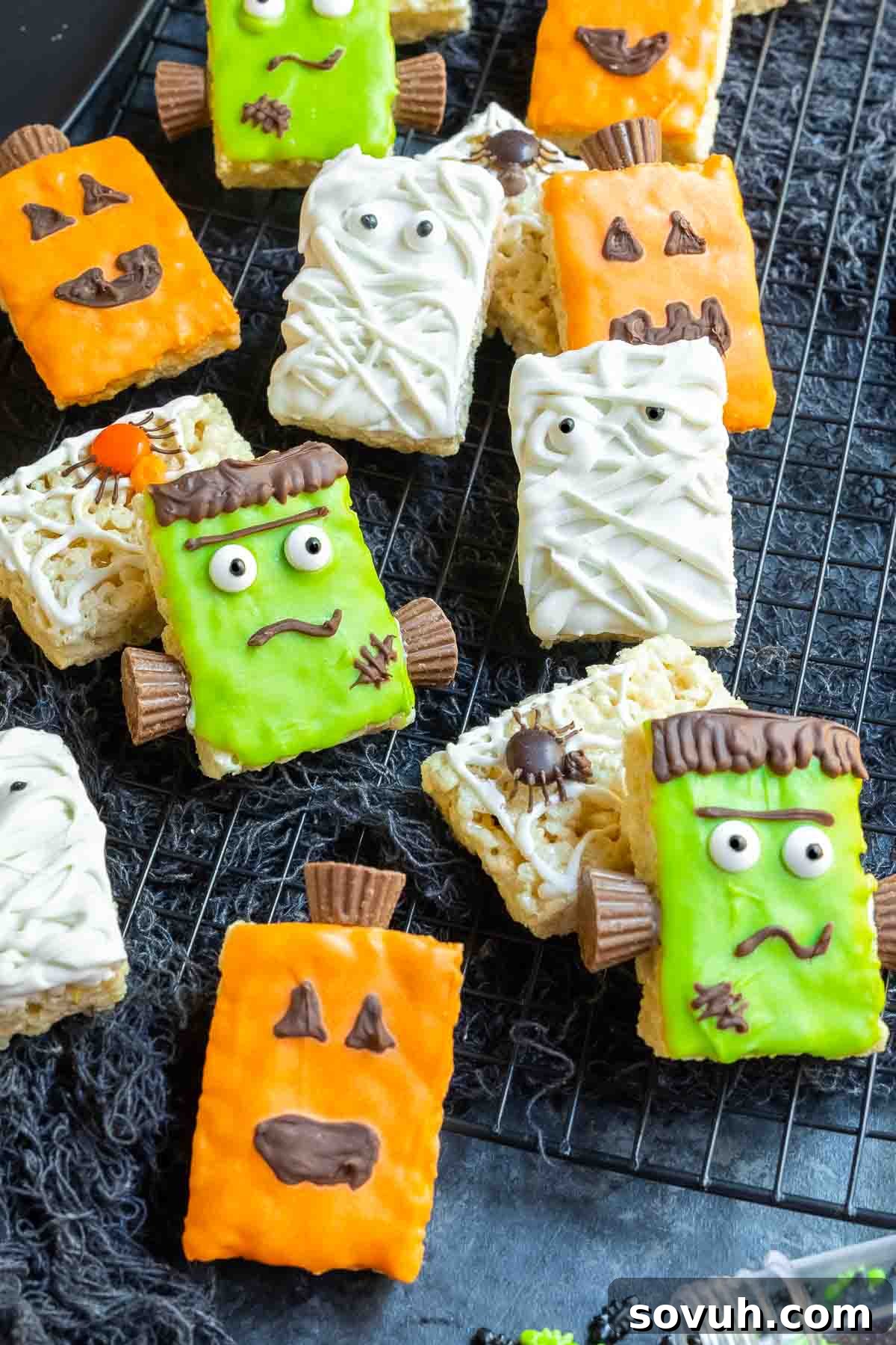 A collection of decorated Halloween Rice Krispies Treats on a black cooling rack, featuring various monster themes.