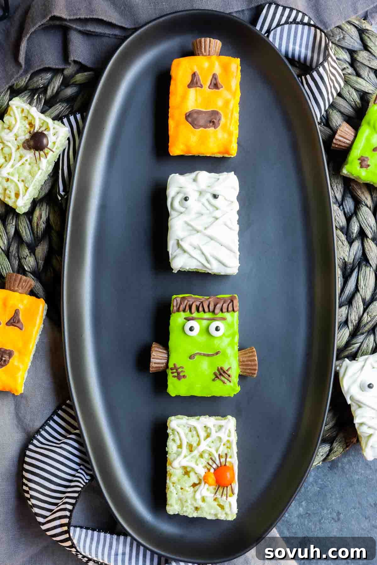 Four distinct Halloween Rice Krispies Treat designs: pumpkin, mummy, Frankenstein, and spider, artfully arranged on a black plate.