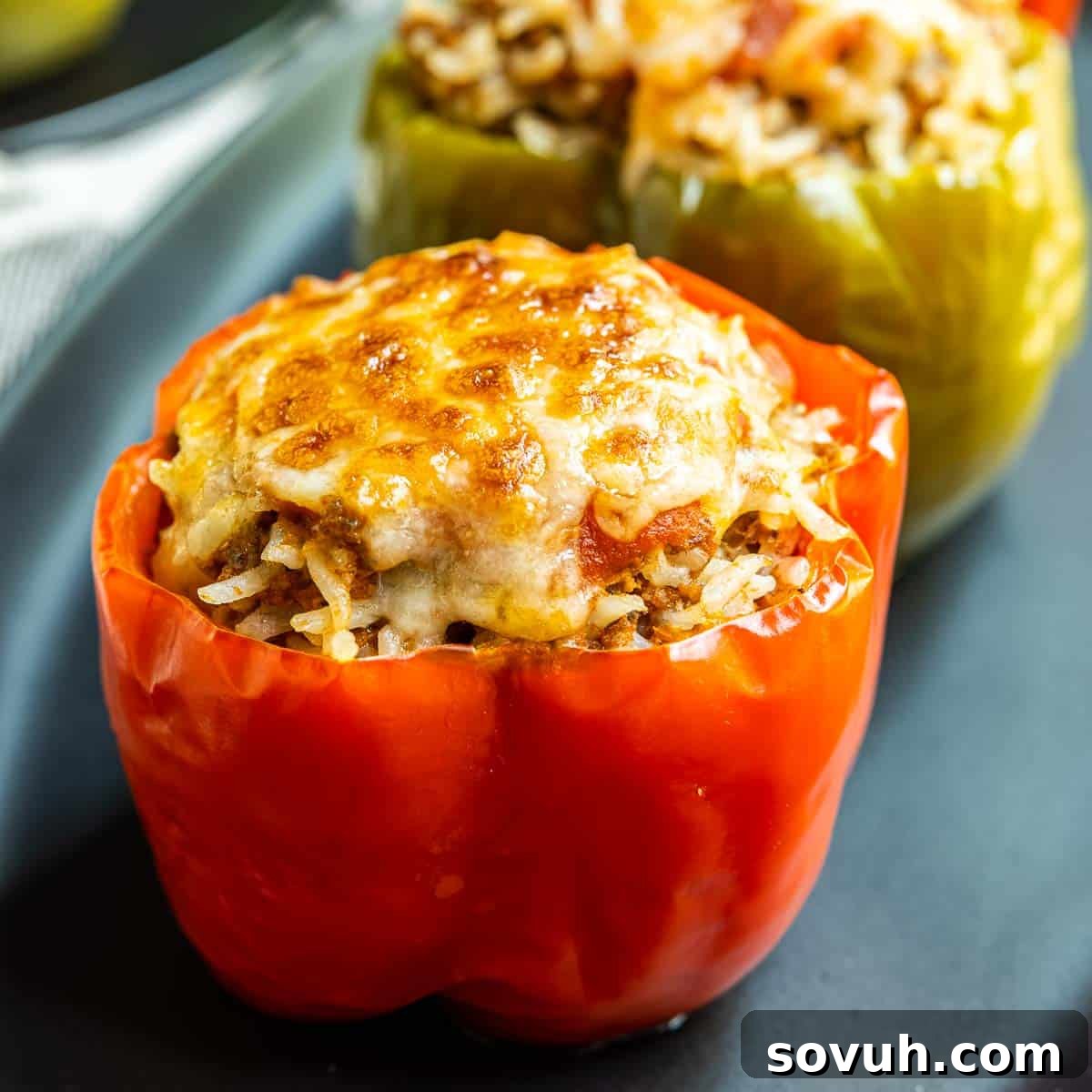 Instant Pot Stuffed Peppers on black plate, showcasing a perfectly cooked and cheesy bell pepper