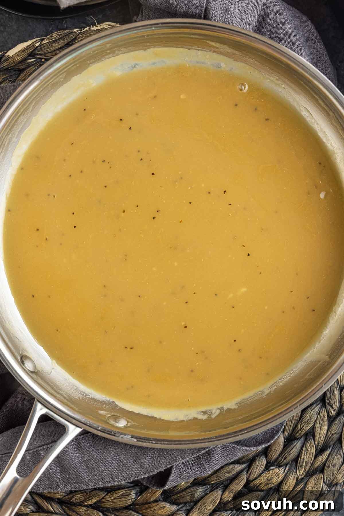Silky smooth Homemade Turkey Gravy simmering gently in a stainless steel skillet.