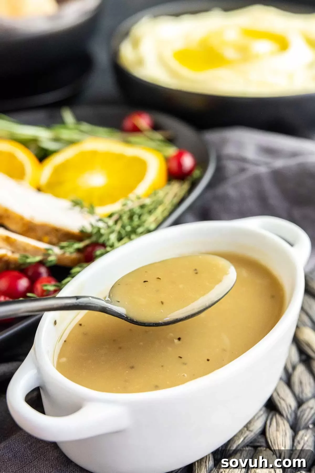 Homemade Turkey Gravy elegantly presented in a white gravy boat with a black serving spoon.