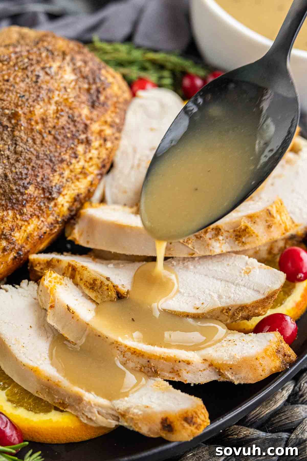 A spoon drizzling rich Homemade Turkey Gravy over tender slices of turkey breast, highlighting its smooth texture.