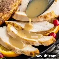 Homemade Turkey Gravy poured on sliced turkey breast