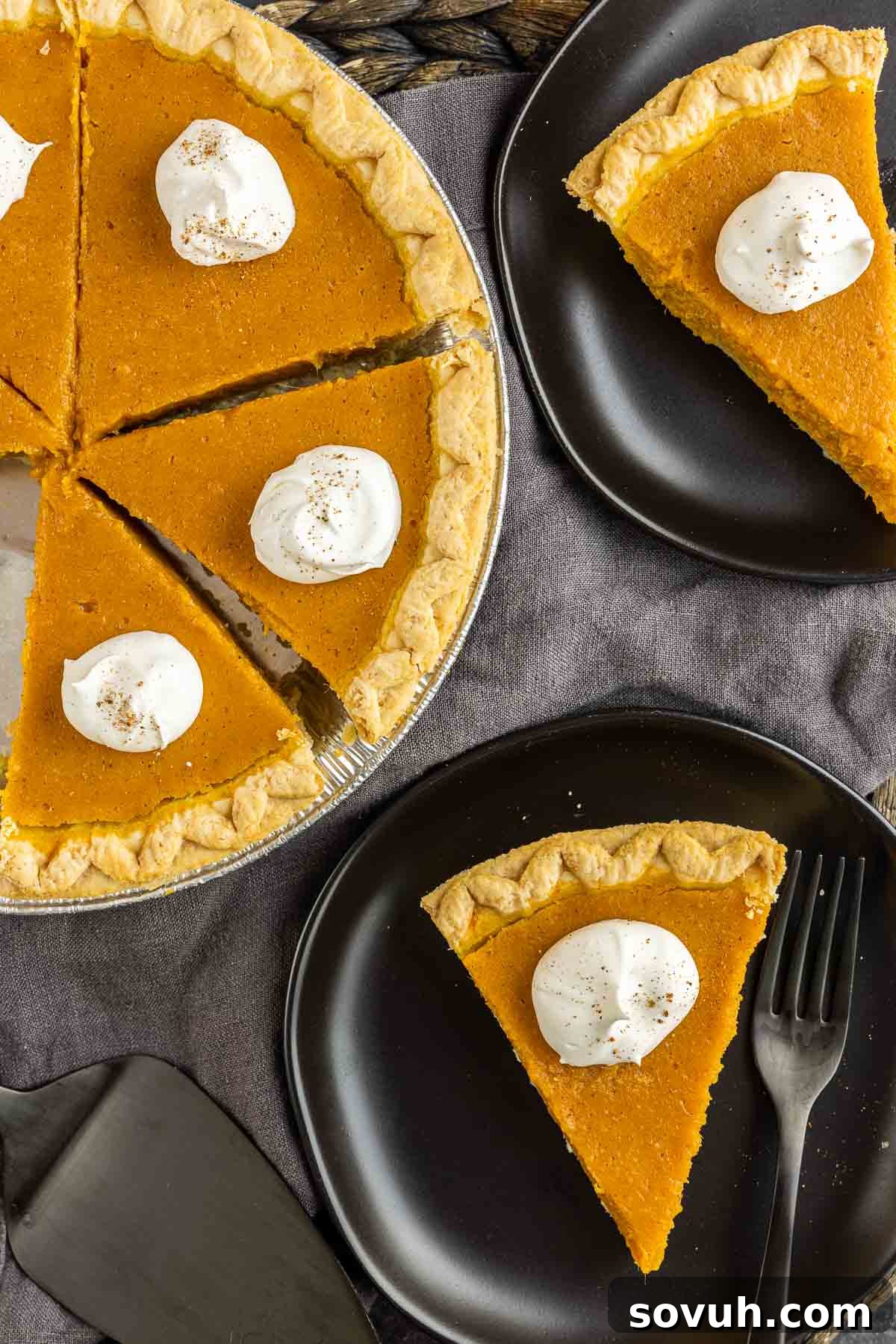 Slices of sweet potato pie on black plates, each adorned with a generous dollop of whipped cream, ready for serving.