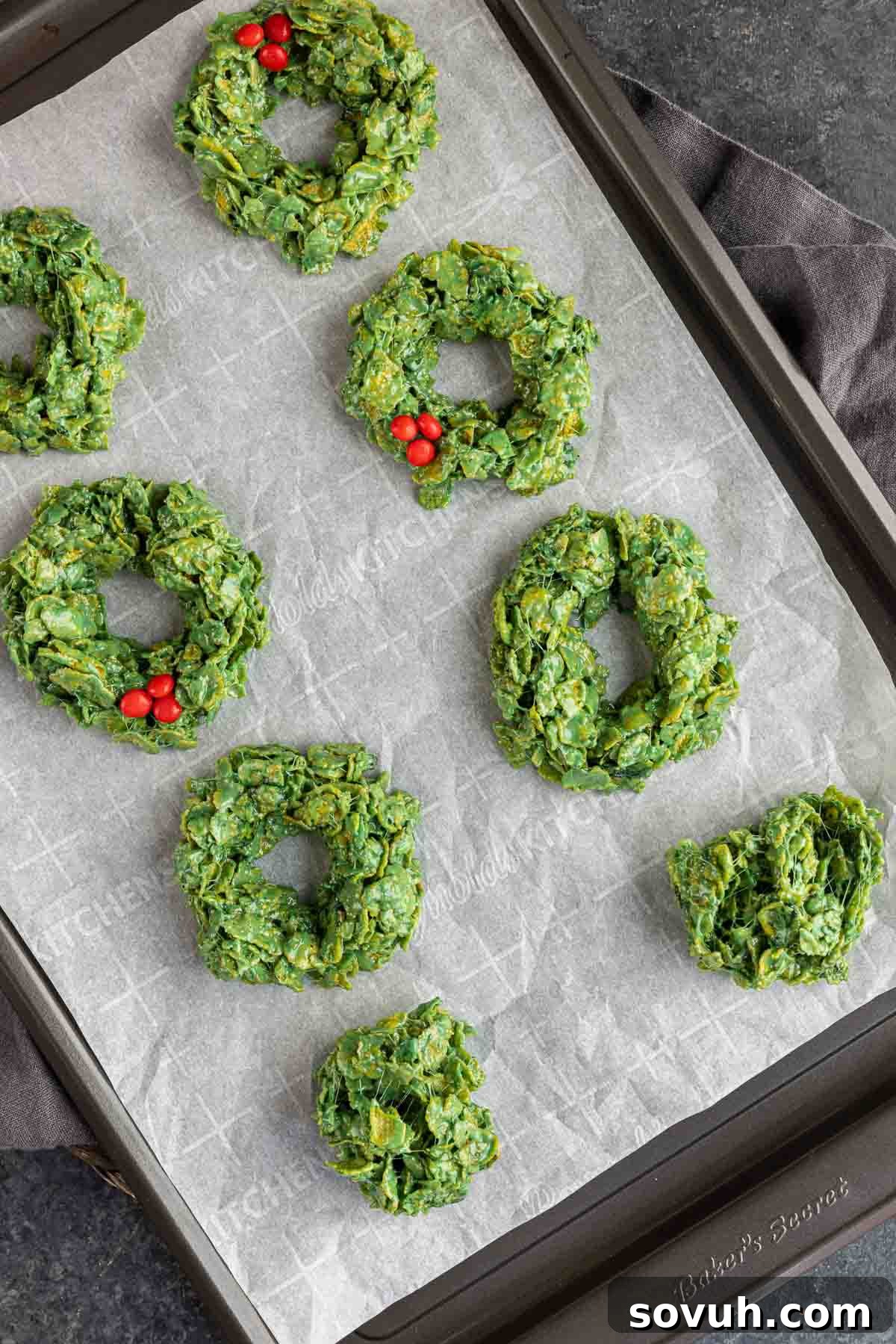 Step-by-step process of making Christmas Wreath Cookies, showing melted marshmallows, mixed cornflakes, and shaping the wreaths.