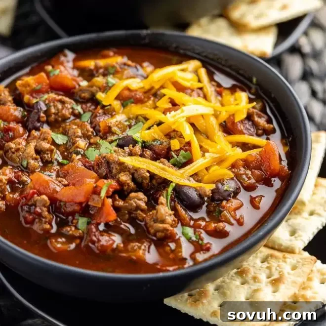 black bowl of Smoky Chipotle Chili topped with shredded cheese
