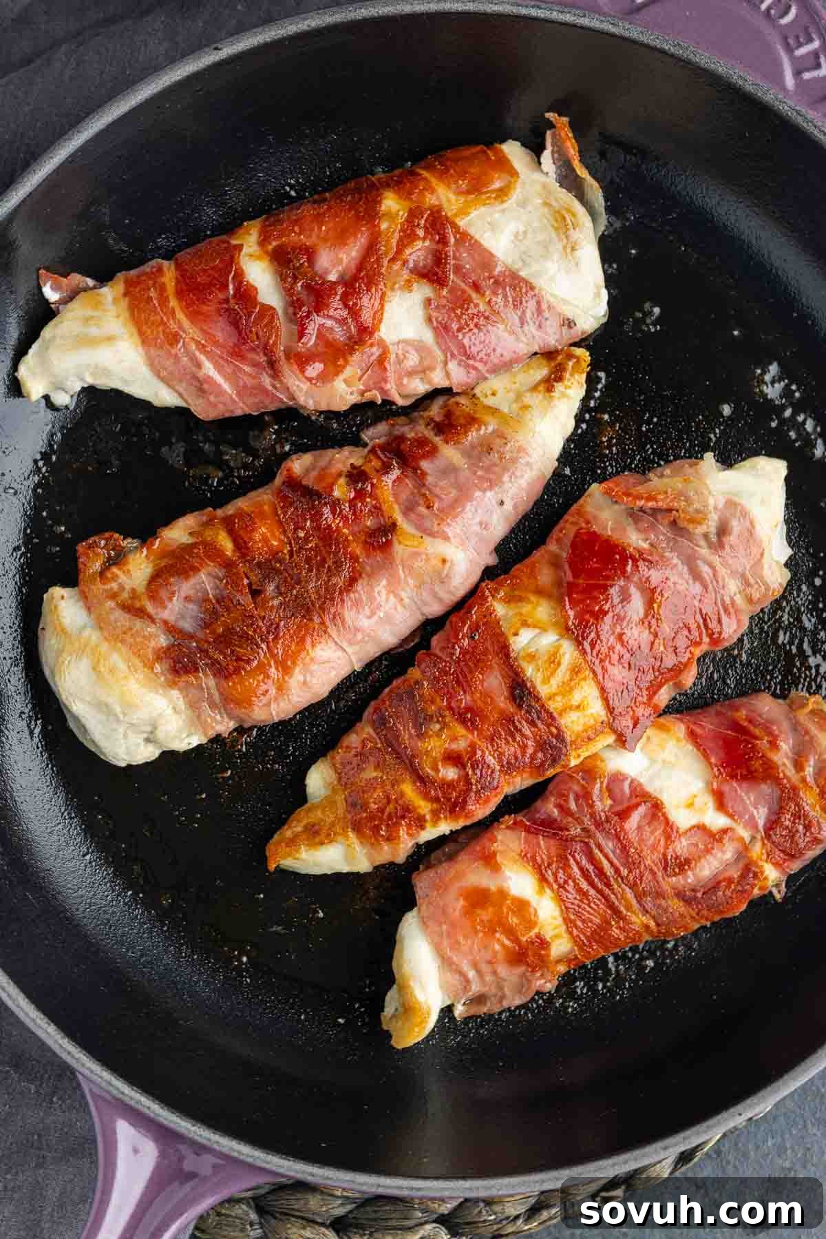 Prosciutto Wrapped Chicken sizzling in a cast iron skillet with the lemon sauce.