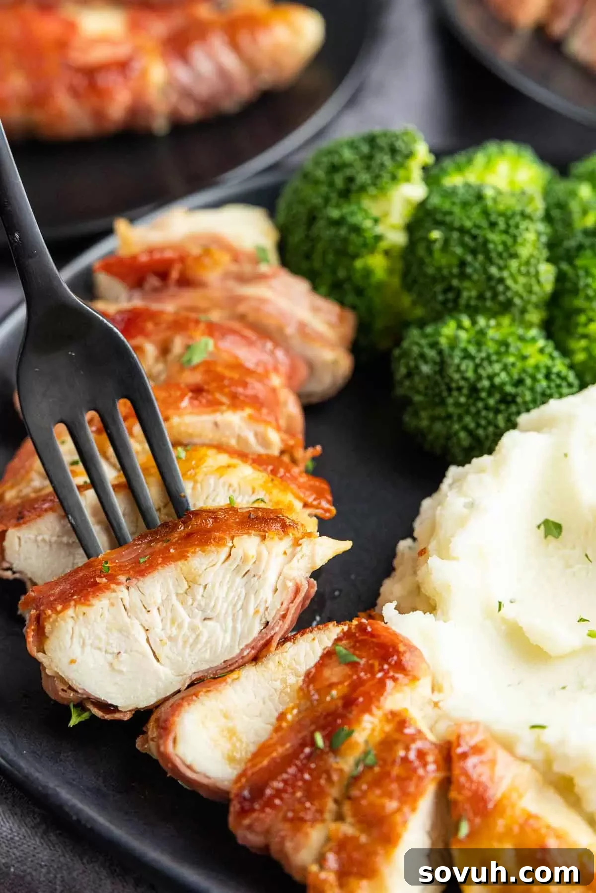 A slice of Prosciutto Wrapped Chicken on a fork, showing the layers of crispy prosciutto and juicy chicken.