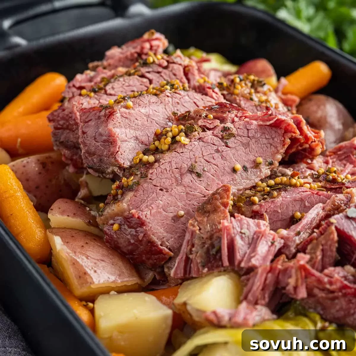Black platter with succulent slices of Instant Pot Corned Beef, accompanied by perfectly cooked cabbage wedges and potatoes.