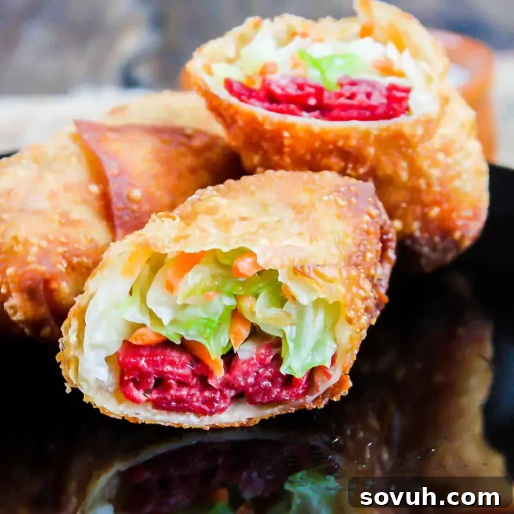 A close-up view of crispy Irish egg rolls, sliced open to reveal a vibrant filling of bright red corned beef, fresh shredded lettuce, and crisp carrots, elegantly arranged on a black plate.