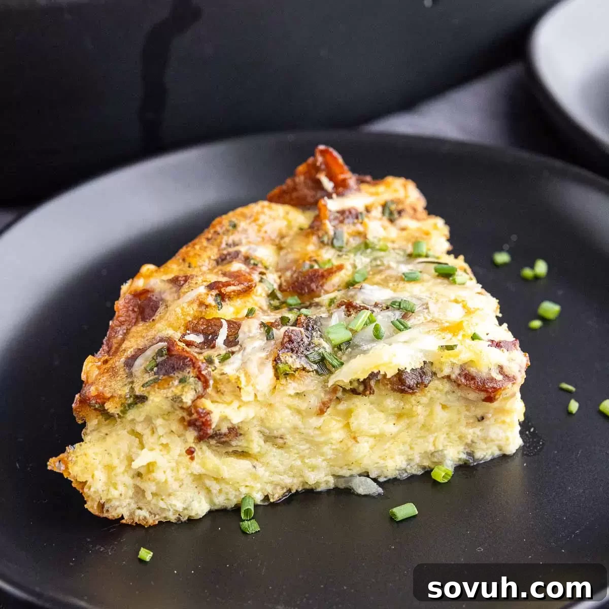 traigle slice of keto quiche Lorraine on a black plate