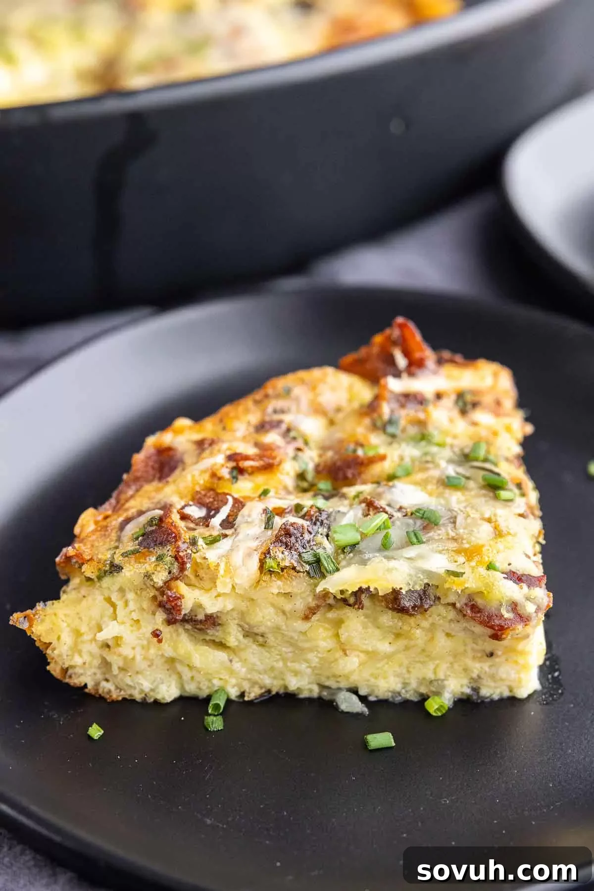 traigle slice of keto quiche Lorraine on a black plate