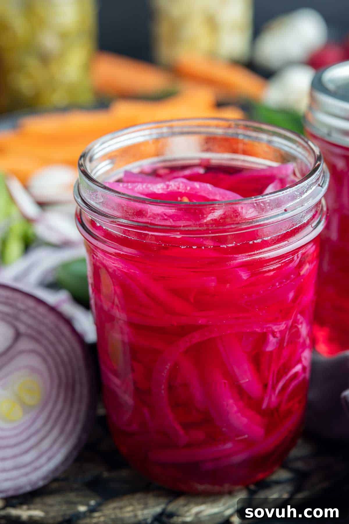 A glass jar filled with beautiful pink Pickled Red Onions