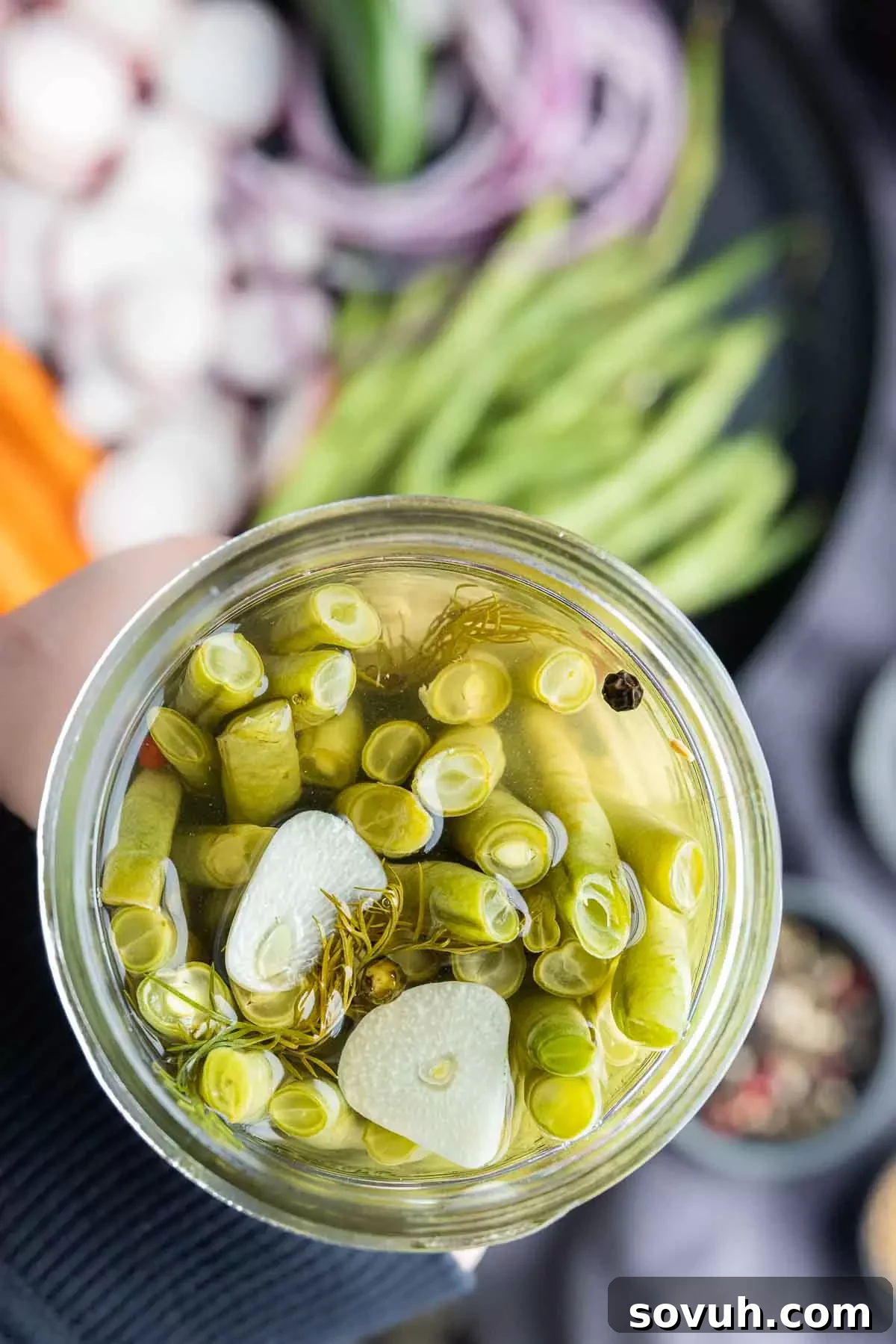 holding a mason jar of pickled green beans