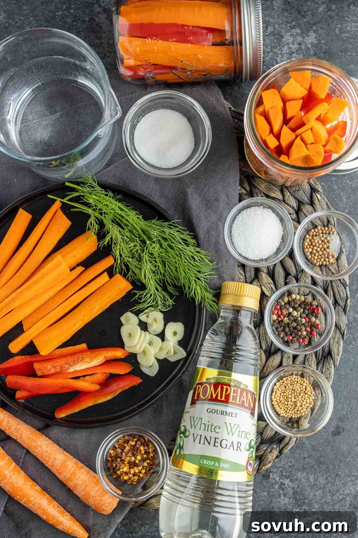 Assorted ingredients laid out for making quick pickled carrots, including carrots, bell pepper, garlic, and spices.