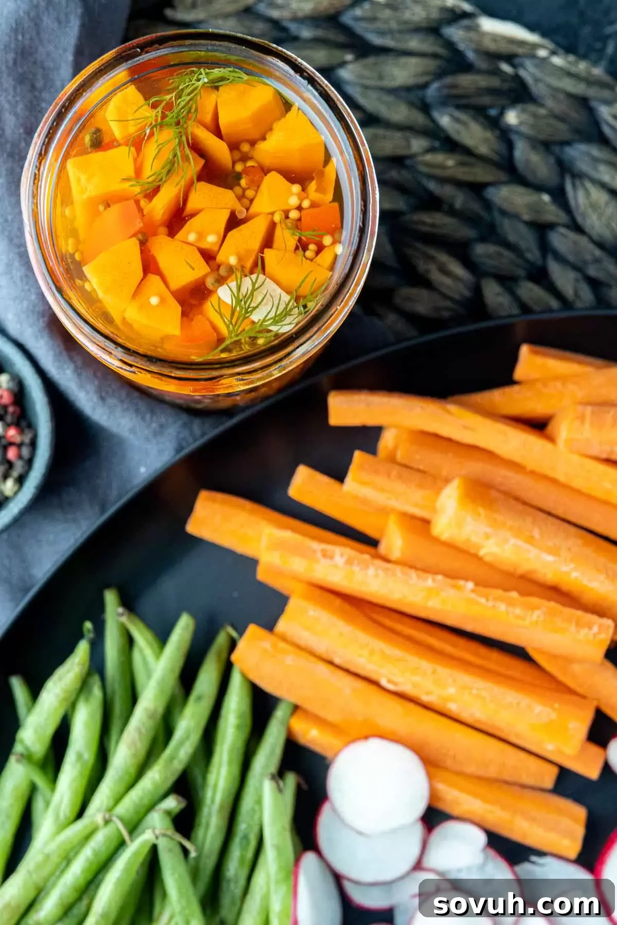 A plate of carrot sticks next to a jar of quick pickled carrots, showcasing their vibrant color and fresh appearance.