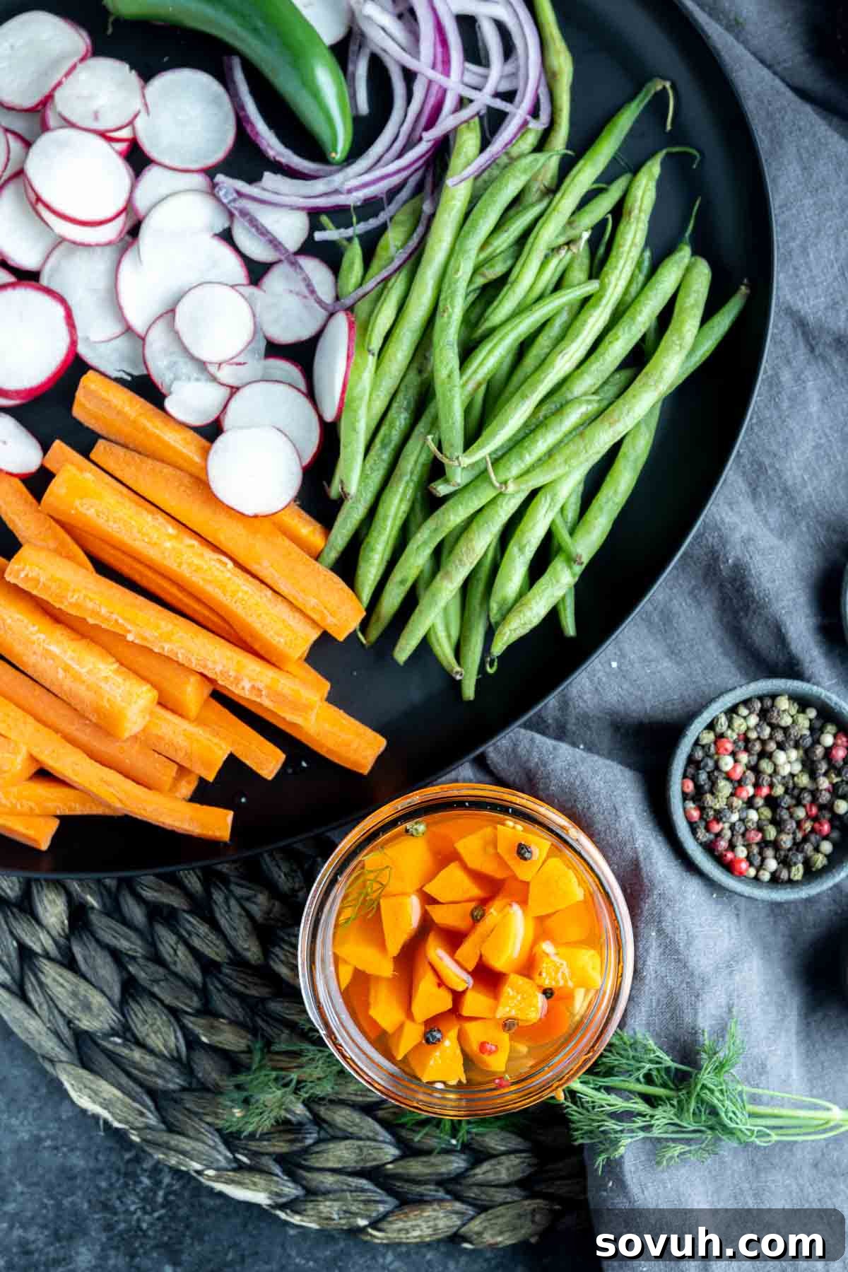 A beautifully arranged black platter featuring quick pickled carrots alongside other fresh vegetables and snacks.