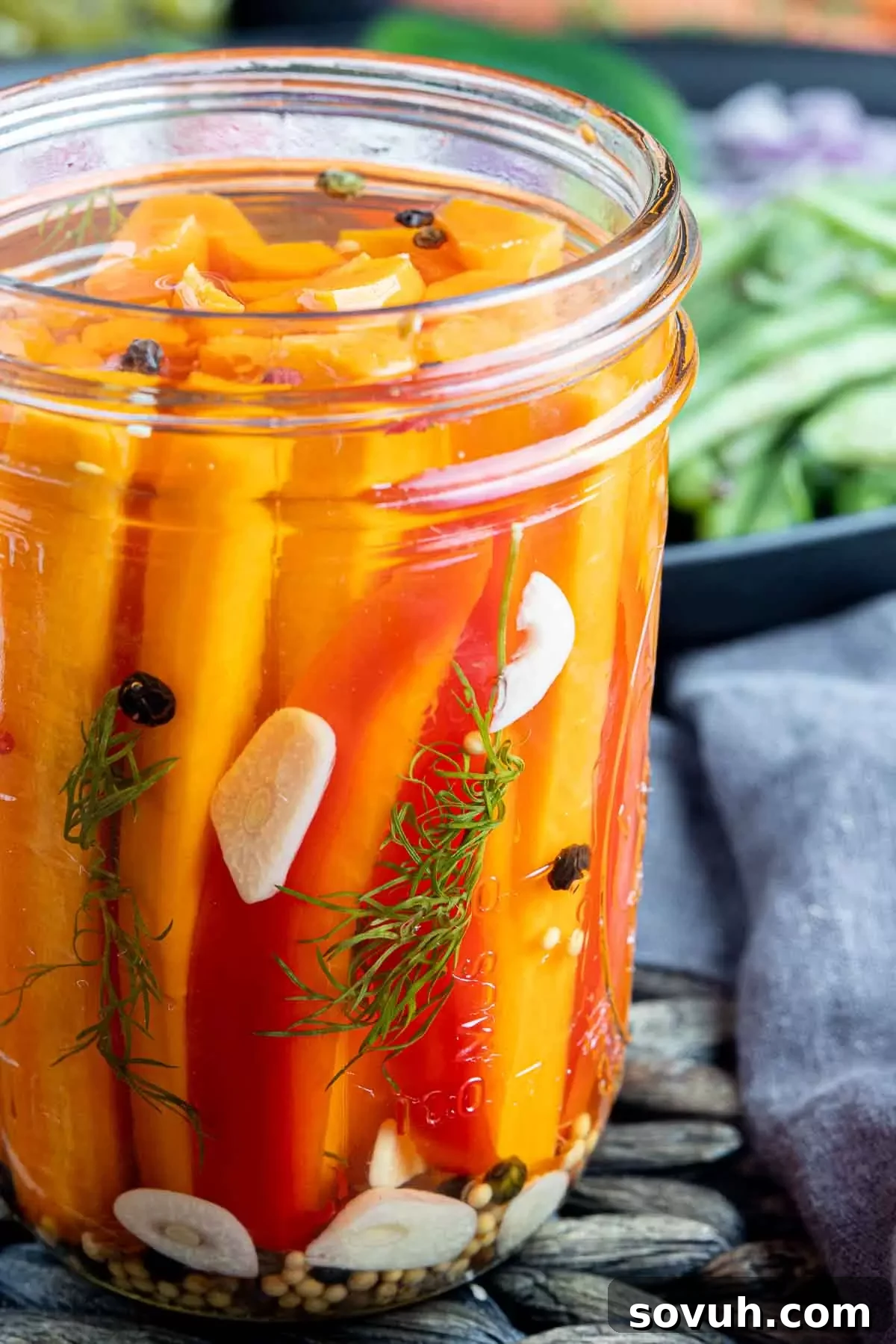 A close-up of quick pickled carrots in a jar, highlighting garlic cloves and red pepper flakes.