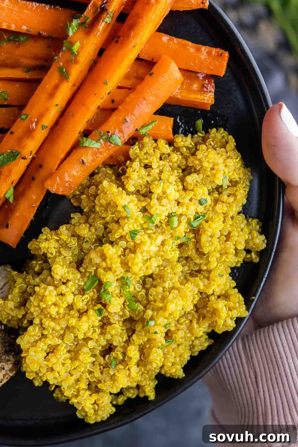 holding a black plate with Turmeric Quinoa and carrots