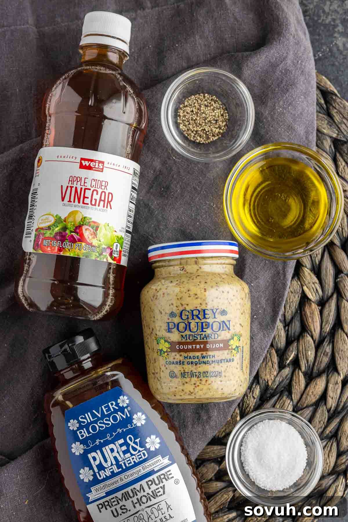 Golden Honey Dijon Dressing 3 Ingredients laid out for making homemade honey mustard dressing including Dijon mustard, honey, apple cider vinegar, olive oil, salt, and pepper.