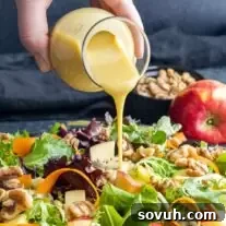 Delicious homemade honey mustard dressing being poured over a fresh salad.