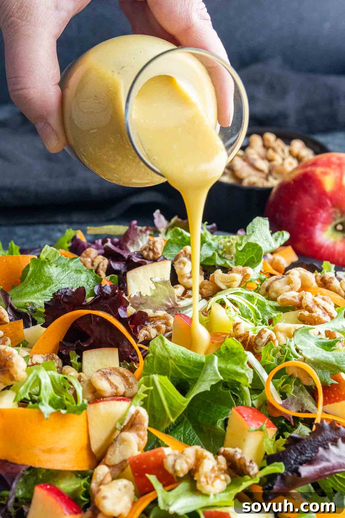 Honey Dijon Dressing being poured on a plate of Apple Walnut Salad