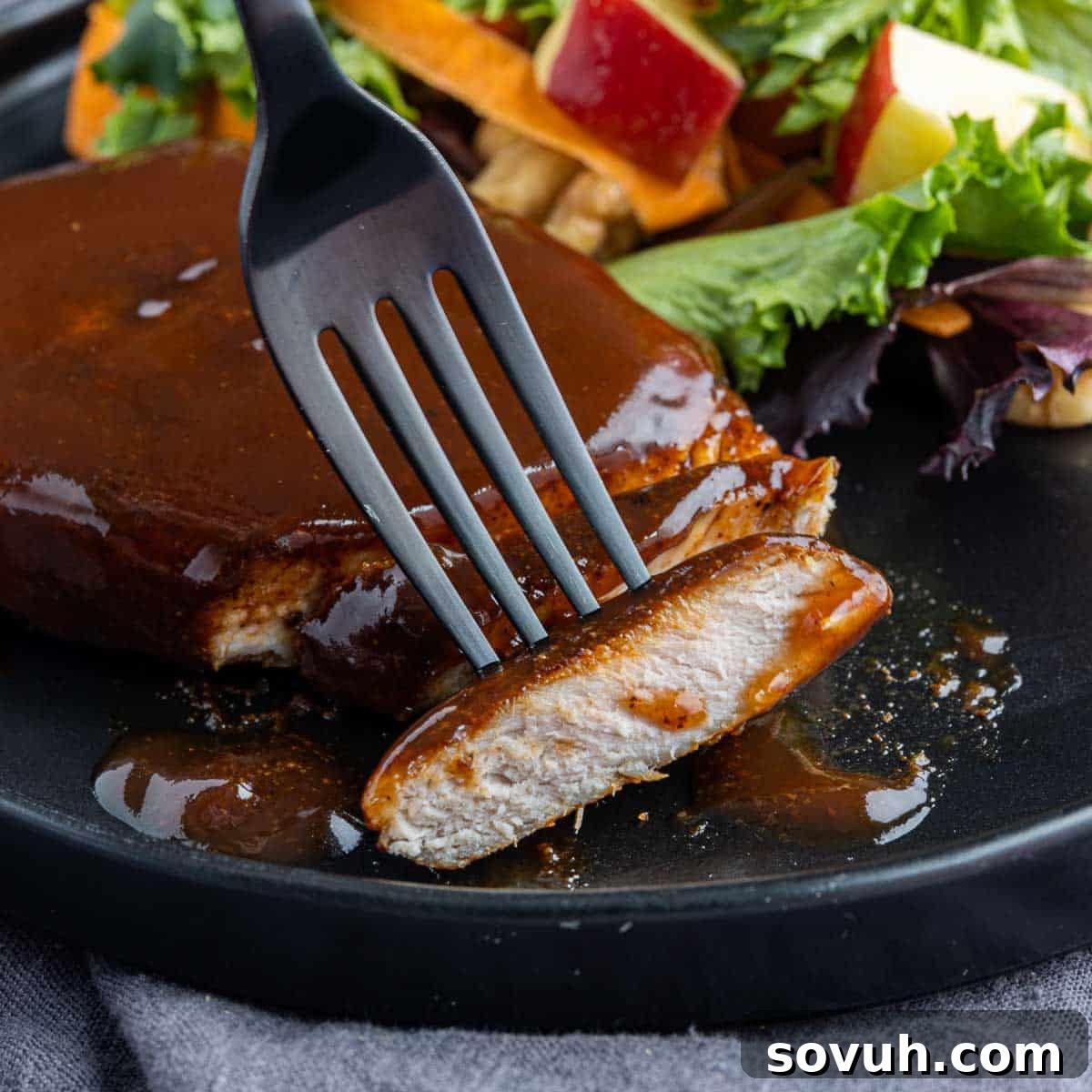 Perfectly cooked Air Fryer BBQ Pork Chops, sliced and ready to serve on a black plate, showcasing their tender interior and caramelized exterior.