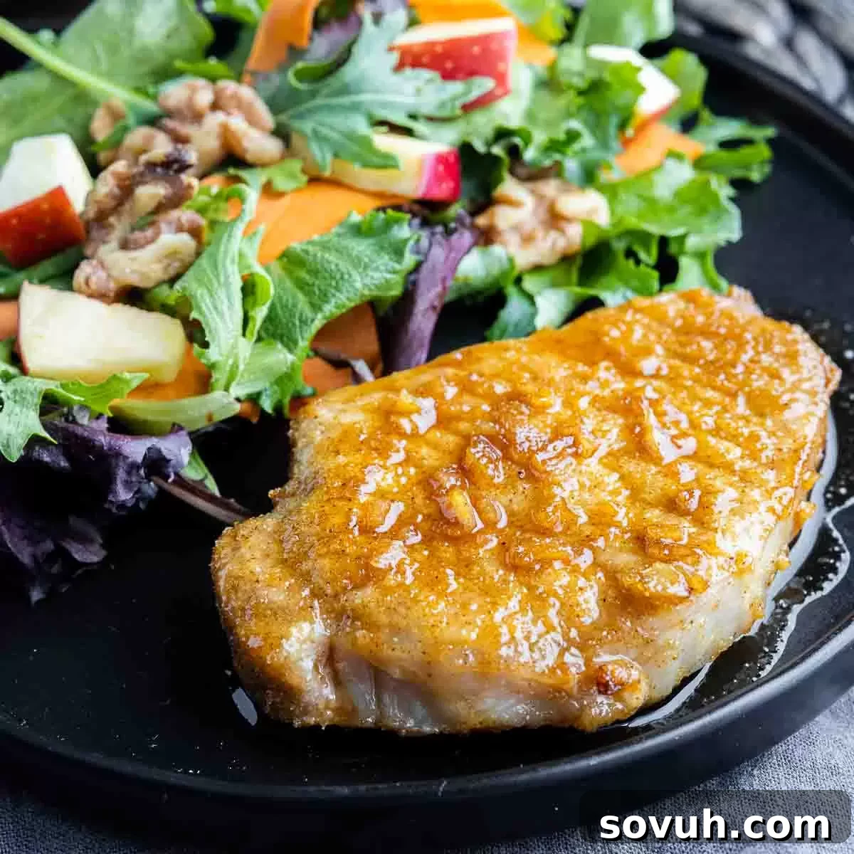 Air Fryer Honey Garlic Pork Chops on a black plate with walnut salad