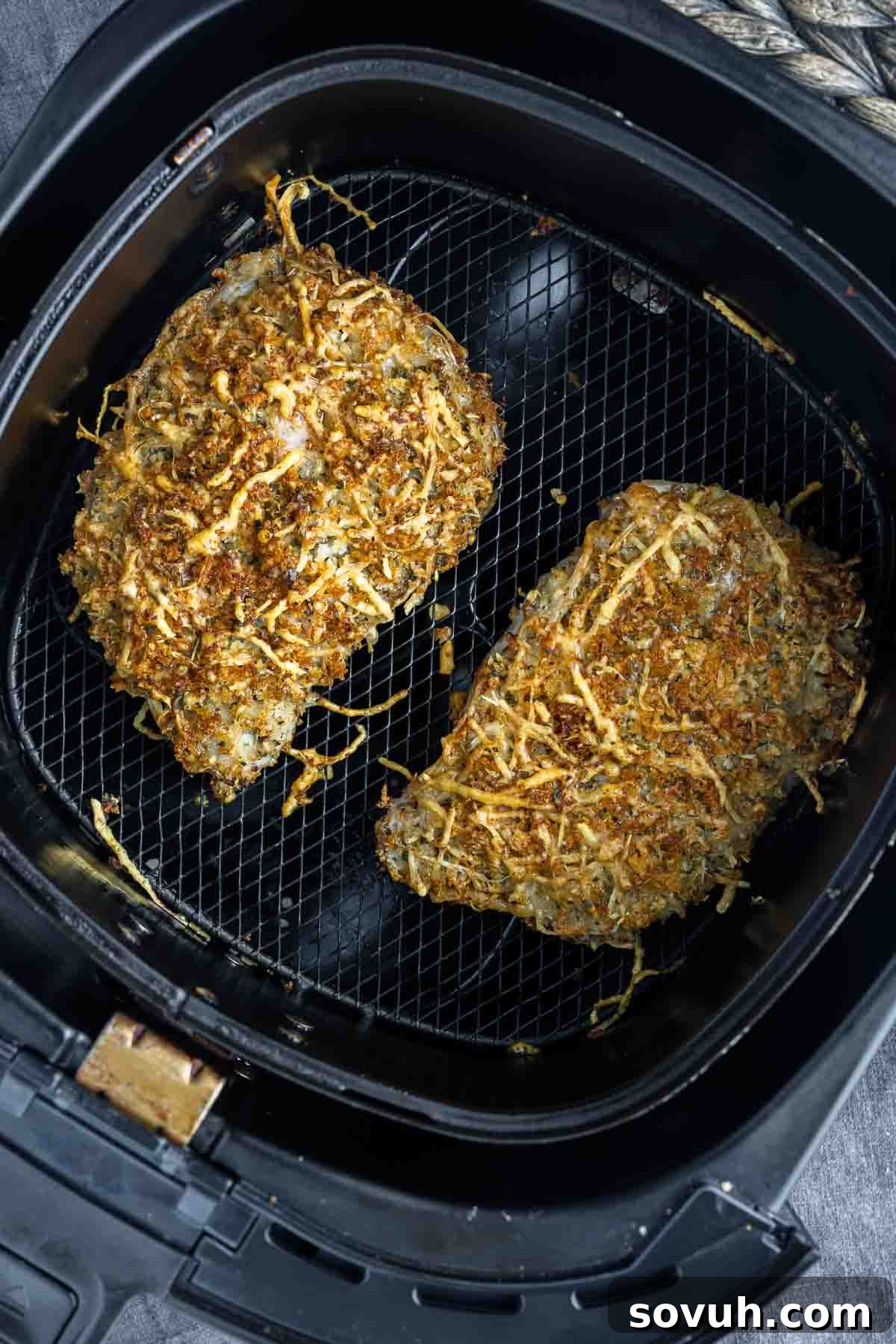 Cooked Air Fryer Parmesan Crusted Pork Chops in the air fryer basket, showing a golden, crispy crust