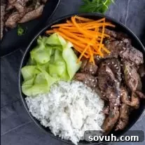 top down of beef bulgogi in a black bowl with rice and vegetables