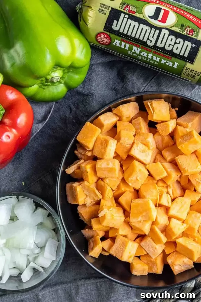 Ingredients for Sweet Potato Hash laid out, including sweet potatoes, bell peppers, onions, and sausage.