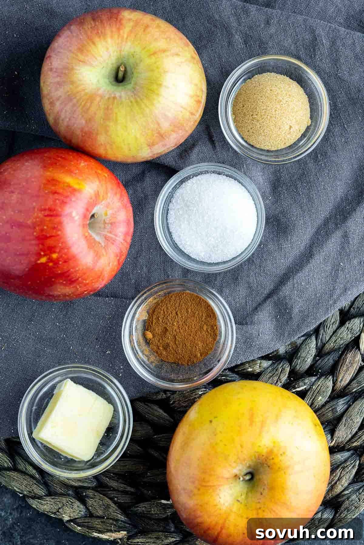 A flat lay photograph showcasing the simple ingredients needed to make Air Fryer Baked Apple Slices: apples, sugars, cinnamon, and butter.