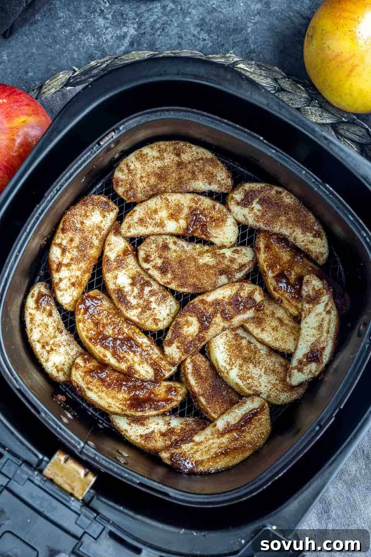 Cinnamon sugar coated apple slices cooking perfectly in an air fryer basket.