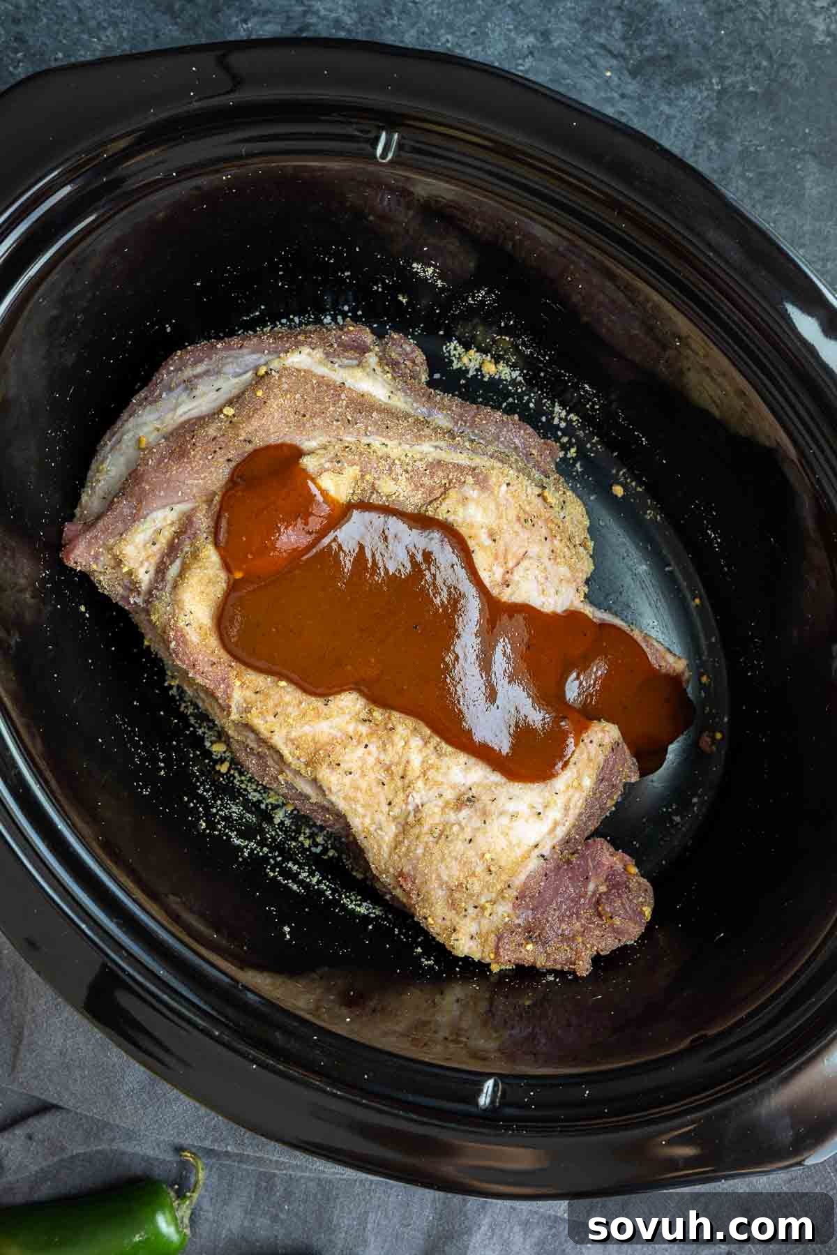 Slow Cooker BBQ Pulled Pork cooking inside a slow cooker, covered in rich BBQ sauce.