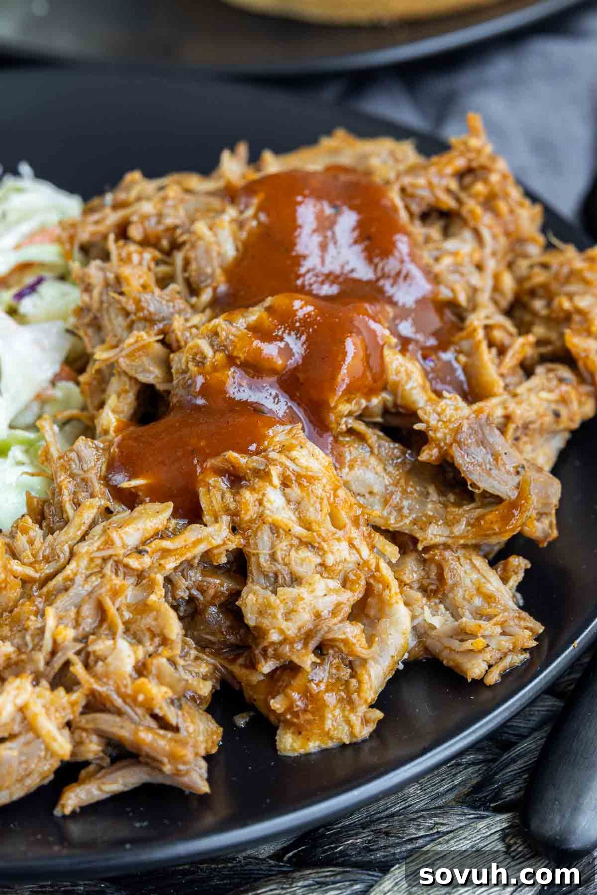 Close-up of Slow Cooker BBQ Pulled Pork with extra BBQ sauce drizzled on top, ready to serve.