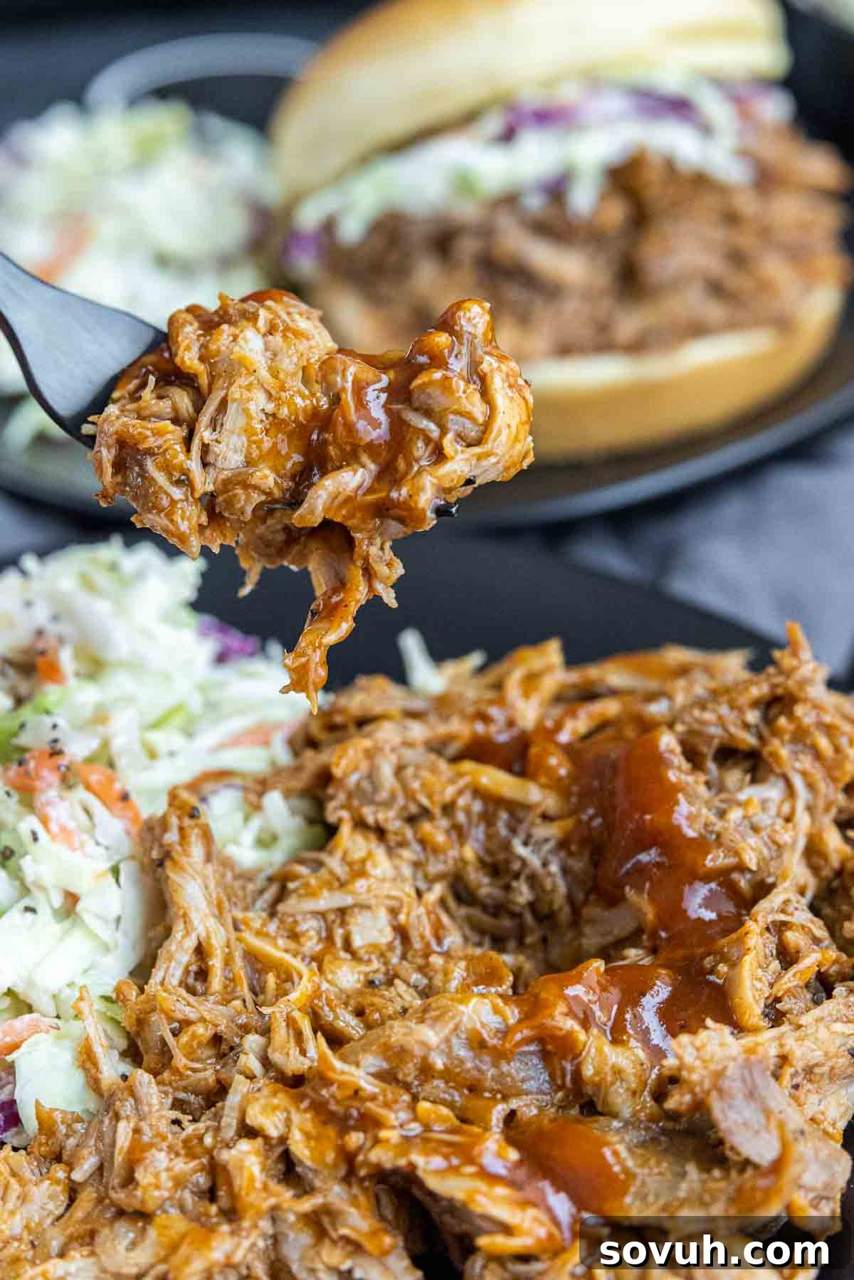A fork holding a generous portion of Slow Cooker BBQ Pulled Pork, showing its tender, shredded texture.